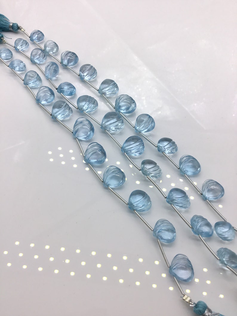 May include: A strand of light blue gemstone beads, each bead is faceted and has a unique shape. The beads are strung on a silver wire and are ready to be used for jewelry making.