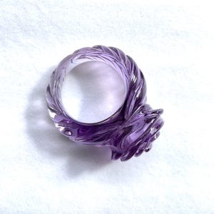 Pode incluir: Um anel de ametista roxo com uma banda torcida e uma configura&ccedil;&atilde;o em forma de rosa.
