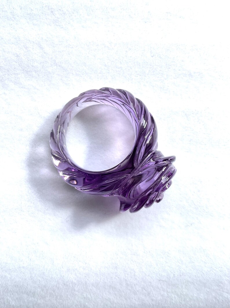 Pode incluir: Um anel de ametista roxo com uma banda torcida e uma configura&ccedil;&atilde;o em forma de rosa.
