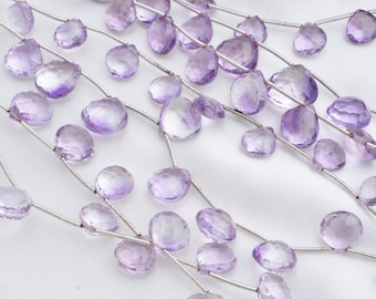 May include: A strand of light purple amethyst gemstone beads, each bead is faceted and shaped like a teardrop. The beads are strung on a silver wire and have a tassel at the end.