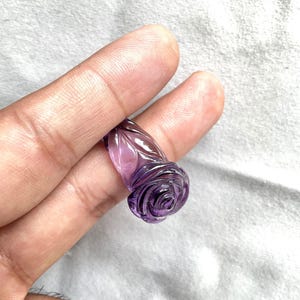 Pode incluir: Um anel de ametista roxa esculpido em forma de rosa.