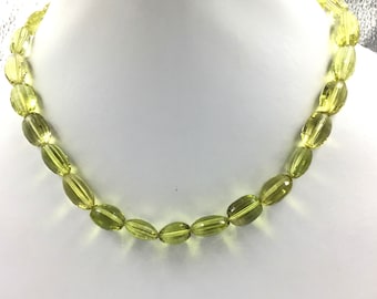 May include: A necklace made of light green oval-shaped beads. The beads are faceted and have a translucent appearance.