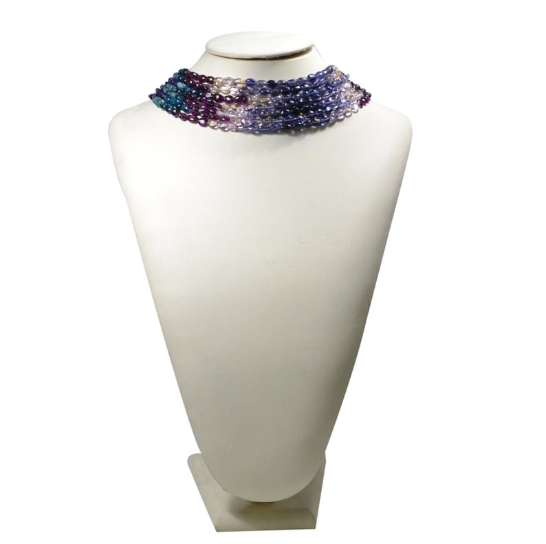 May include: A multi-strand necklace made of purple, blue, and pink beads. The necklace is displayed on a white mannequin bust.