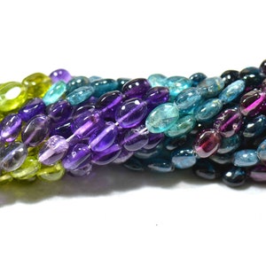 May include: A strand of oval-shaped gemstone beads in shades of green, blue, purple, and pink. The beads are arranged in a gradient pattern, with the green beads at one end and the pink beads at the other.