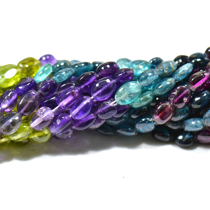 May include: A strand of oval-shaped gemstone beads in shades of green, blue, purple, and pink. The beads are arranged in a gradient pattern, with the green beads at one end and the pink beads at the other.