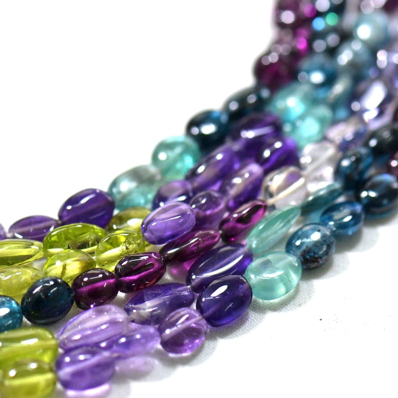 May include: A strand of colorful gemstone beads, including amethyst, green aventurine, and blue apatite, in a variety of shades and sizes. The beads are oval-shaped and have a smooth, polished finish.