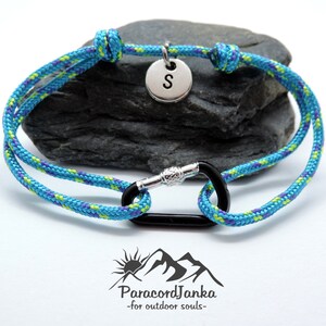 Pu&ograve; includere: Un braccialetto in paracord blu e verde con un moschettone nero e un ciondolo argentato con la lettera "S".