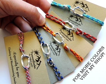Può includere: Cinque braccialetti in paracord colorati con moschettoni argentati. Ogni braccialetto ha un'etichetta con il testo "Paracord Janka - for outdoor souls." Il testo "FOR MORE COLORS VISIT MY SHOP!" è visibile nell'angolo in basso a destra.