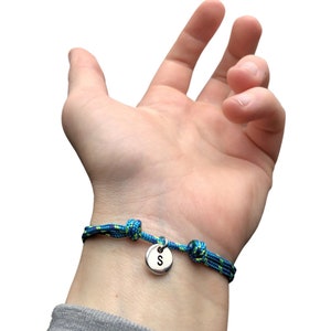 Pu&ograve; includere: Un braccialetto in corda blu e verde con un ciondolo d'argento con la lettera "S" su di esso.