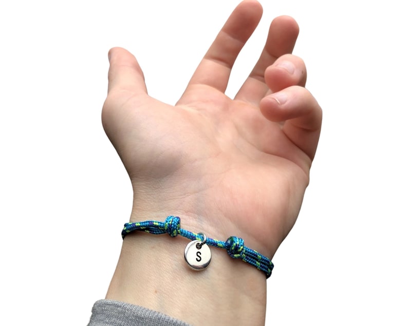 Pu&ograve; includere: Un braccialetto in corda blu e verde con un ciondolo d'argento con la lettera "S" su di esso.