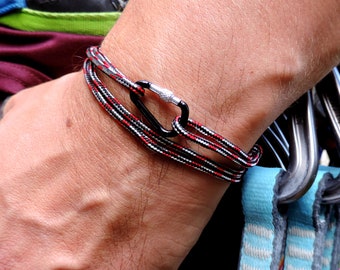 May include: A black and red braided rope bracelet with a silver carabiner clasp.