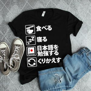 May include: Black t-shirt with white text that says "食べる" (eat), "寝る" (sleep), "日本語を勉強する" (study Japanese), and "わかります" (I understand).