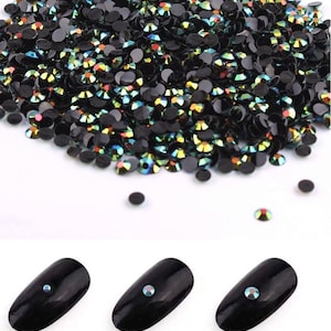 May include: A large pile of iridescent black rhinestones in various sizes. Three black nail tips are shown with a rhinestone on each, labelled 2mm, 3mm, and 4mm.