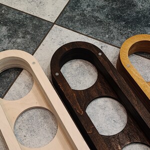 May include: Three wooden wall mounted organizers with three circular cutouts each. The organizers are made of different wood types: natural wood, dark stained wood, and light stained wood.