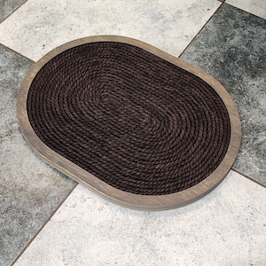May include: A brown oval-shaped cat scratching post with a rope surface and a wooden frame.