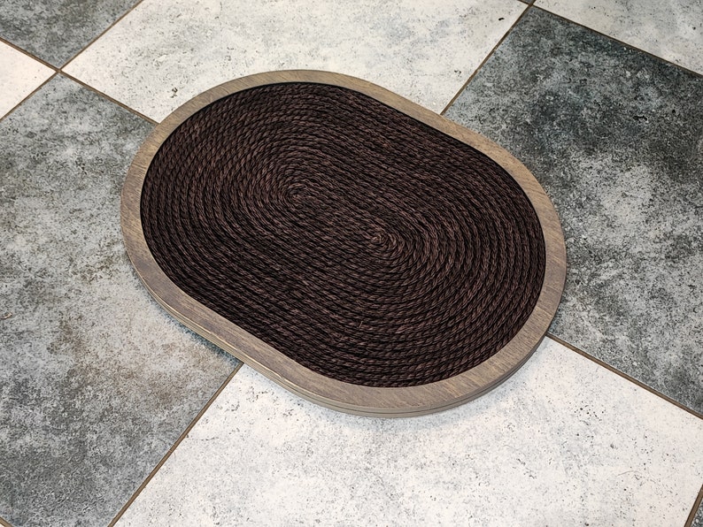 May include: A brown oval-shaped cat scratching post with a rope surface and a wooden frame.