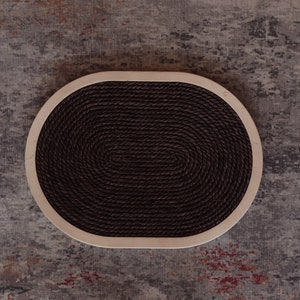 May include: A round, oval-shaped cat scratching post with a brown rope surface and a light wood frame.