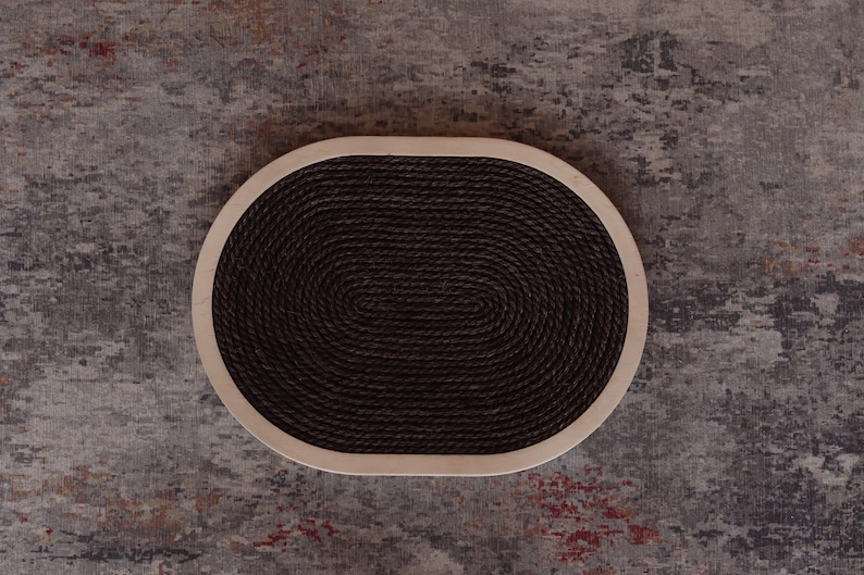 May include: A round, oval-shaped cat scratching post with a brown rope surface and a light wood frame.