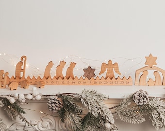 May include: A wooden advent calendar featuring a long base with numbers 1 through 24, topped with carved figures including a shepherd, sheep, wise men, a dark wood star, an angel, and a nativity scene with a star at the top of the stable structure.
