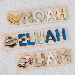 以下が含まれることがあります： カラフルな文字とペグハンドルが付いた3つの木製ネームパズル。「NOAH」、「ELIJAH」、「LIAM」という名前です。各パズルには、黄色い飛行機、青と黄色のボート、赤と白の救急車など、さまざまな乗り物が描かれています。