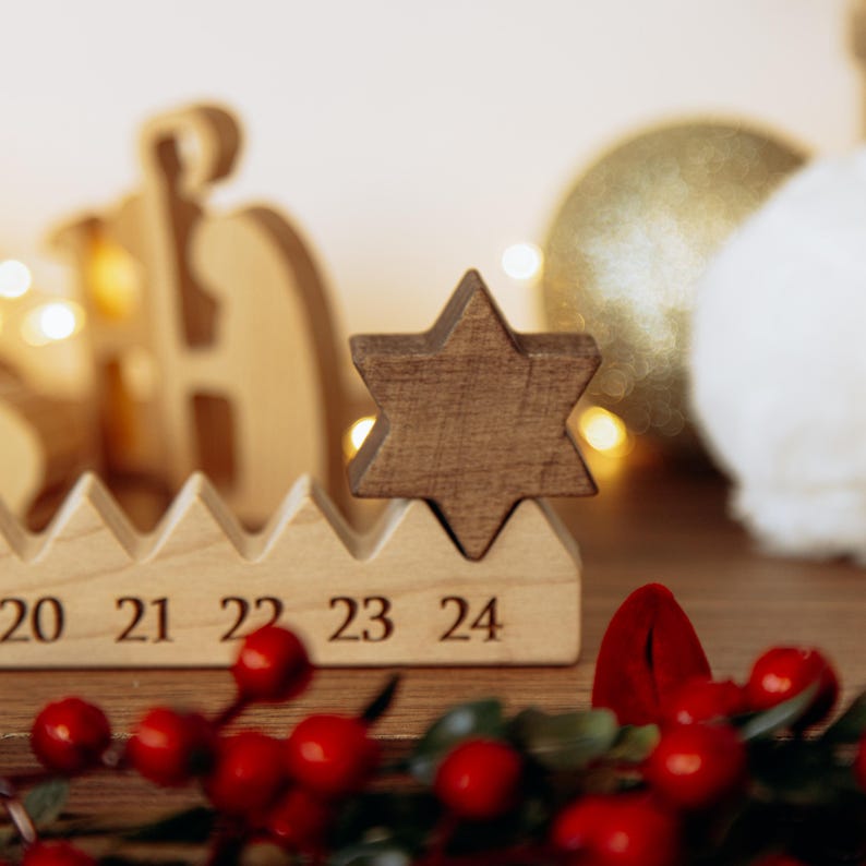 Pu&ograve; includere: Una base per calendario dell'avvento in legno chiaro con i numeri 20, 21, 22, 23 e 24 incisi sulla parte anteriore. Un pezzo di legno marrone scuro a forma di stella &egrave; posizionato sopra il numero 24, fungendo da segnaposto per l'ultimo giorno.