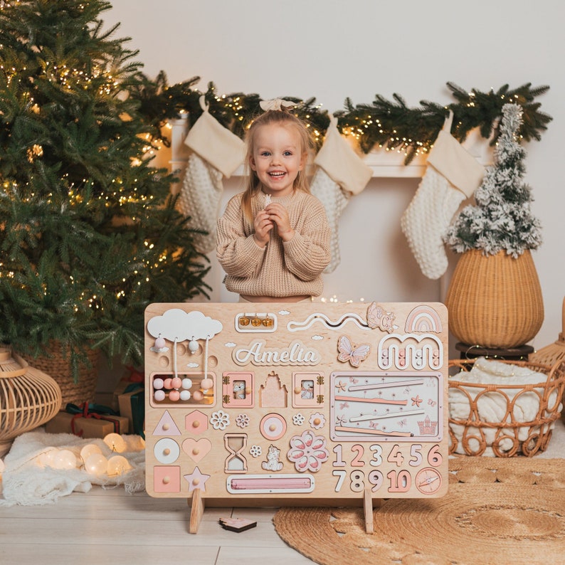 The photo shows a large Busy Board, which contains many moving elements that develop a child's logical thinking and fine motor skills.
This photo shows a board in pink colors.
Perfect for a baby's girl birthday present.