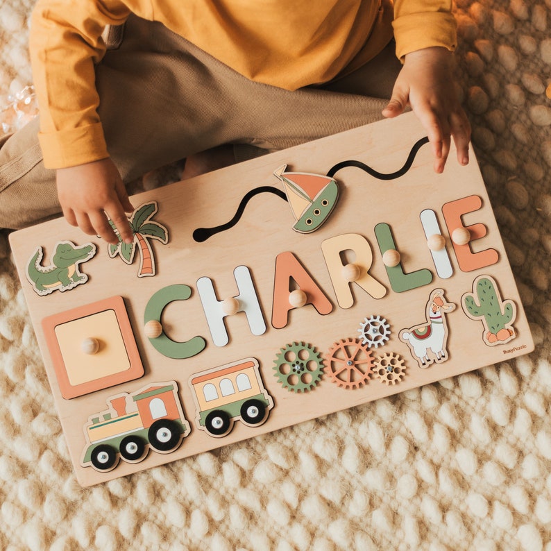 Custom Busy Board with moving elements that develop fine motor skills.
Montessori board with mirror, train, gears, llama, crocodile and cactus.
1st Birthday Personalized Gift For Kids.
For additional cost you can add a pegs for letters.