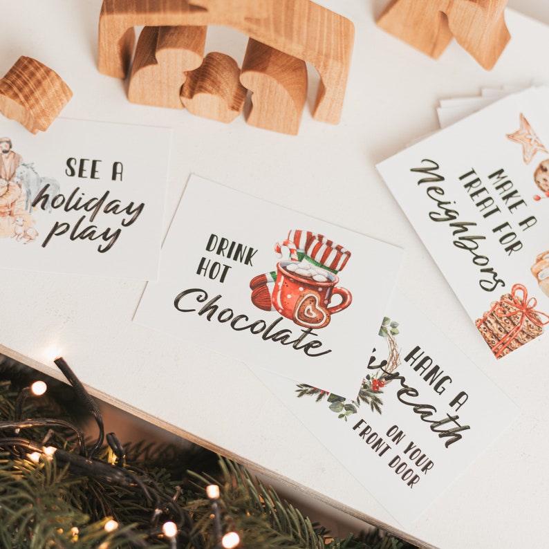 May include: A set of six Christmas-themed cards with watercolor illustrations and text. The cards include the phrases "See a holiday play", "Drink hot chocolate", "Make a treat for neighbors", "Hang a wreath on your front door", "Decorate a gingerbread house", and "Sing Christmas carols".