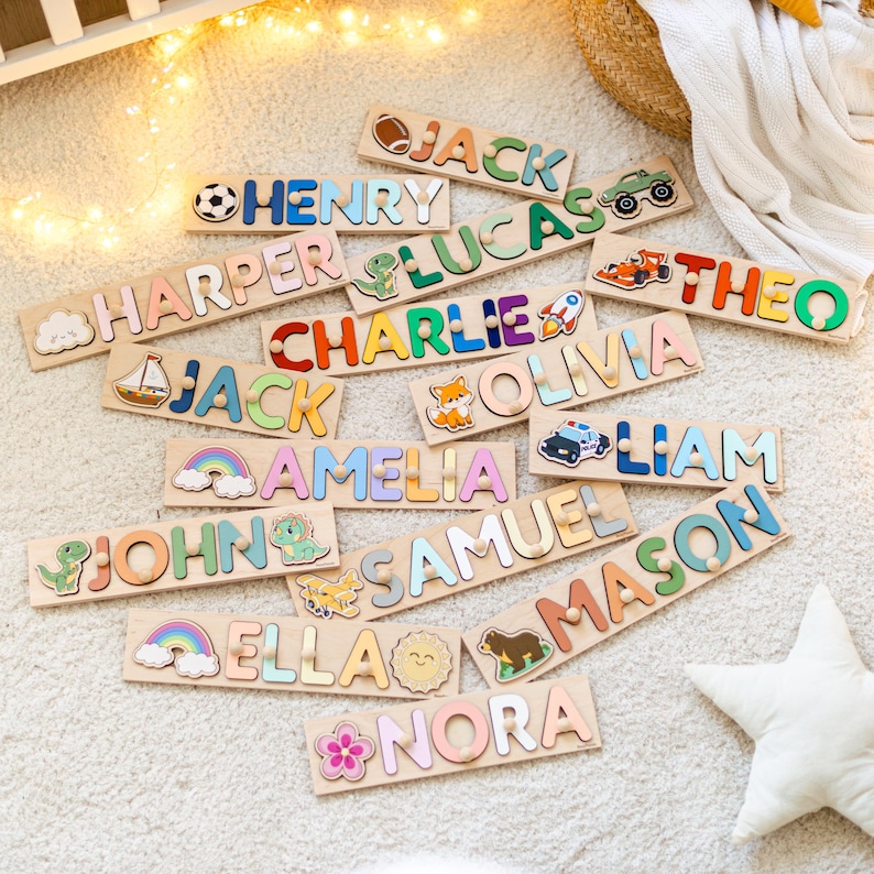 Pode incluir: Uma cole&ccedil;&atilde;o de quebra-cabe&ccedil;as de madeira com letras coloridas e v&aacute;rios &iacute;cones como uma bola de futebol, dinossauro, foguete, arco-&iacute;ris e animais. Cada placa exibe um nome &uacute;nico, incluindo Jack, Henry, Harper, Lucas, Theo, Charlie, Olivia, Amelia, Liam, John, Samuel, Mason, Ella e Nora.