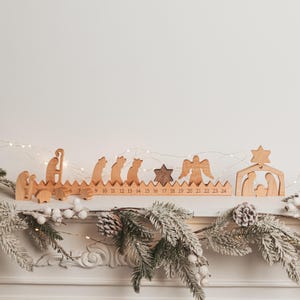 Pu&ograve; includere: Un calendario dell'avvento in legno con una base lunga che presenta i numeri da 1 a 24 incisi lungo il bordo. Il set include varie figure in legno intagliato che rappresentano una scena della nativit&agrave;, tra cui persone, animali, un angelo e una stella.