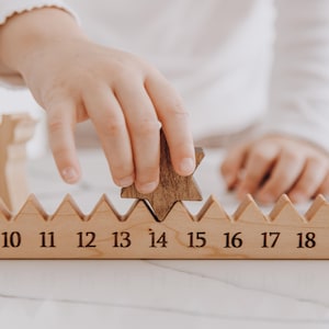 Pu&ograve; includere: Una pista numerica in legno chiaro con un bordo superiore seghettato a forma di montagna e i numeri da 10 a 18 incisi in nero. Un pezzo di legno tinto scuro a forma di stella viene inserito nella fessura tra i numeri 14 e 15.