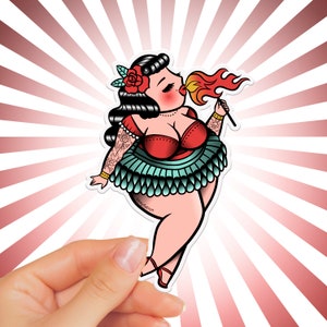 May include: A colorful sticker featuring a pin-up style illustration of a woman with red hair, wearing a red and green outfit, blowing a flame from her mouth. The sticker has a white background with red and white stripes radiating out from the center.