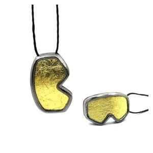 May include: A gold and silver necklace with a pendant shaped like a pair of ski goggles.
