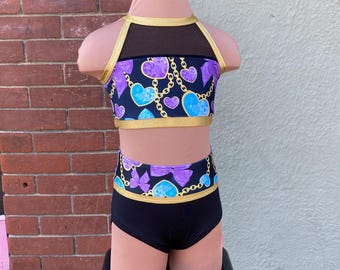 May include: A black dance leotard with a purple and blue heart print and gold chain accents. The leotard has a mesh top and a high-waisted bottom.