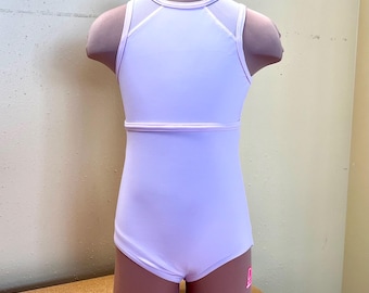 Puede incluir: Maillot de color lila claro sobre un maniquí. Presenta un cuello alto con detalles de malla, una banda horizontal en la cintura y espalda escotada. Un pequeño logotipo rosa es visible en la pierna derecha.