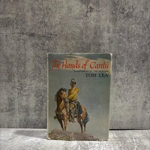 May include: Vintage book titled "The Hands of Cantú" by Tom Lea. The cover art depicts a man in historical attire on horseback. The book has a worn appearance, suggesting it is an antique.