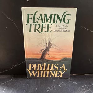 May include: A hardcover book titled "Flaming Tree" by Phyllis A. Whitney. The cover features a leafless tree silhouette against a sunset backdrop of orange, yellow, and green hues. The title is in green, and the author's name is in gold.
