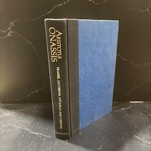 May include: A hardcover book titled "Aristotle Onassis" with a black spine and blue cover. The title is in gold lettering. The author's name and publisher are also visible.