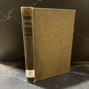 May include: A vintage book titled "Engineering Drawing" by French. The book has a dark brown spine with gold lettering and a tan cover. The book is standing upright on a dark surface.