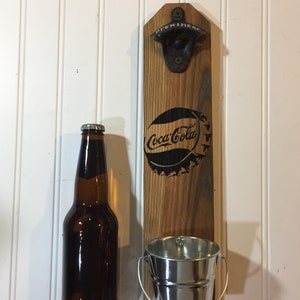 Apribottiglie Coca Cola stile vintage su pallet di recupero in legno.  Coca Cola montato a parete in legno con benna di cattura del tappo zincato.