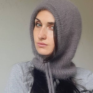 May include: A grey hooded knit hat with a long, dangling tie. The hat is made of a soft, fuzzy material.