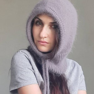 May include: A soft, grey hooded cowl with a long, flowing scarf. The cowl is made of a fuzzy yarn and has a loose, comfortable fit.