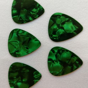 May include: Five green guitar picks with a marbled pattern. The picks are shaped like a triangle with rounded edges.