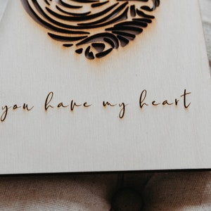 Puede incluir: Una tarjeta de madera con un dise&ntilde;o de coraz&oacute;n cortado con l&aacute;ser y el texto "you have my heart" escrito en cursiva.