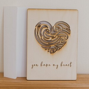 Puede incluir: Una tarjeta de madera con un dise&ntilde;o de coraz&oacute;n cortado con l&aacute;ser y el texto "you have my heart".