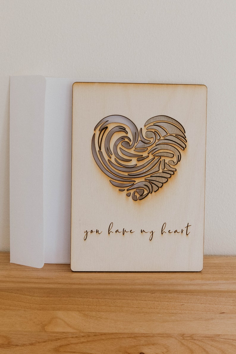 Puede incluir: Una tarjeta de madera con un dise&ntilde;o de coraz&oacute;n cortado con l&aacute;ser y el texto "you have my heart".