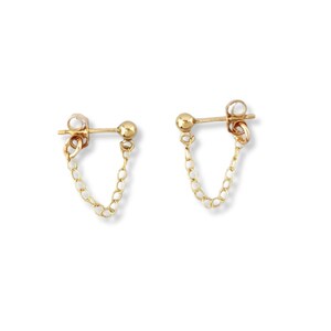 May include: A pair of gold-colored chain earrings. Each earring features a small ball stud connected to a delicate chain that dangles below. The earrings are displayed against a white background.