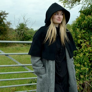woman wearing a short black fleece cape with the hood up