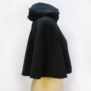 Side view of a black fleece short cape with a hood. The tiny cloak is shown on a mannequin.