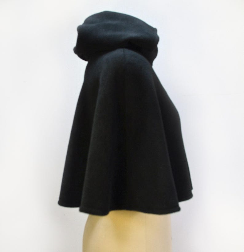 Side view of a black fleece short cape with a hood. The tiny cloak is shown on a mannequin.